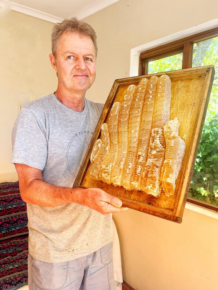Nicholas, the beekeeper behind Bees' Choice, holding a wooden frame of fresh honeycomb